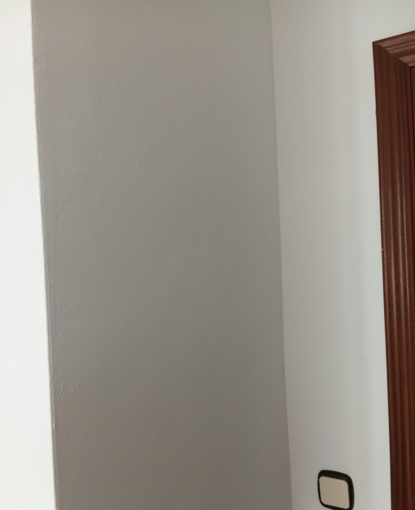 Pilar pintado en gris junto a pared blanca y marco de madera