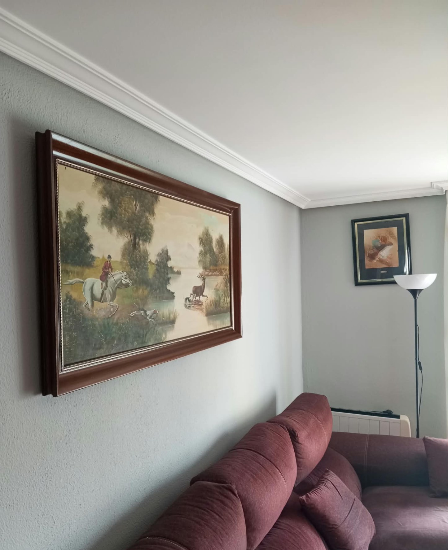 Pared de salón pintada en gris junto a sofá y molduras blancas