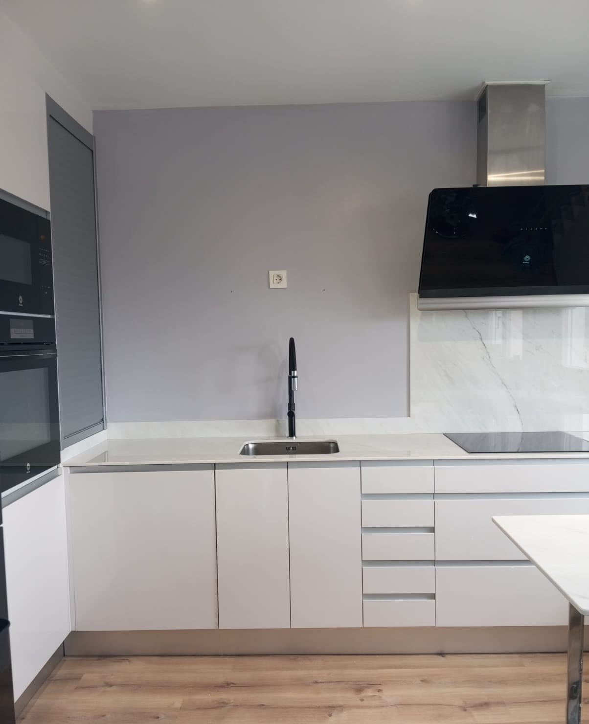 Cocina moderna con pared pintada en gris lila sobre el fregadero