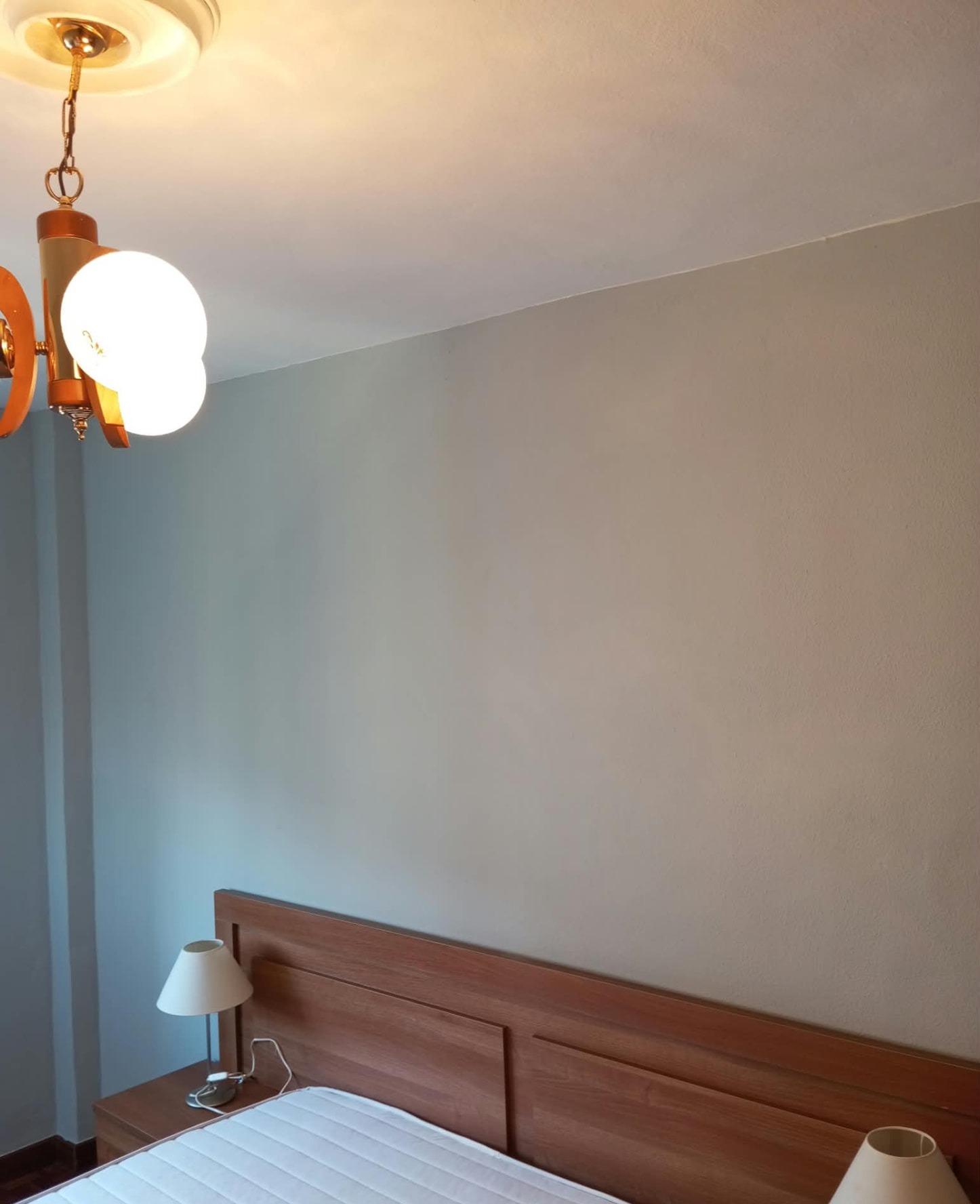 Dormitorio con pared de cabecero pintada en gris y techo blanco