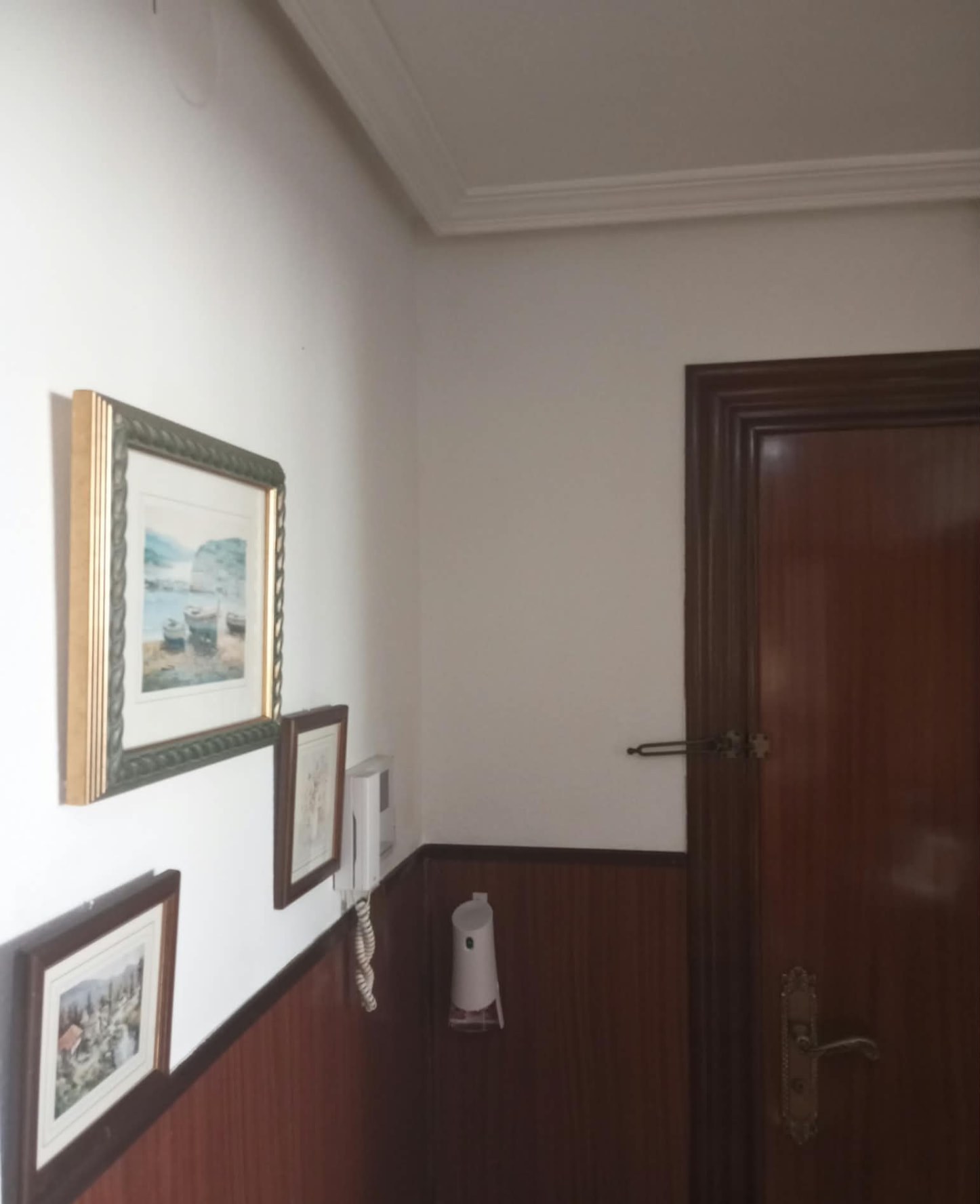 Pasillo pintado en blanco con friso y puerta de madera barnizada
