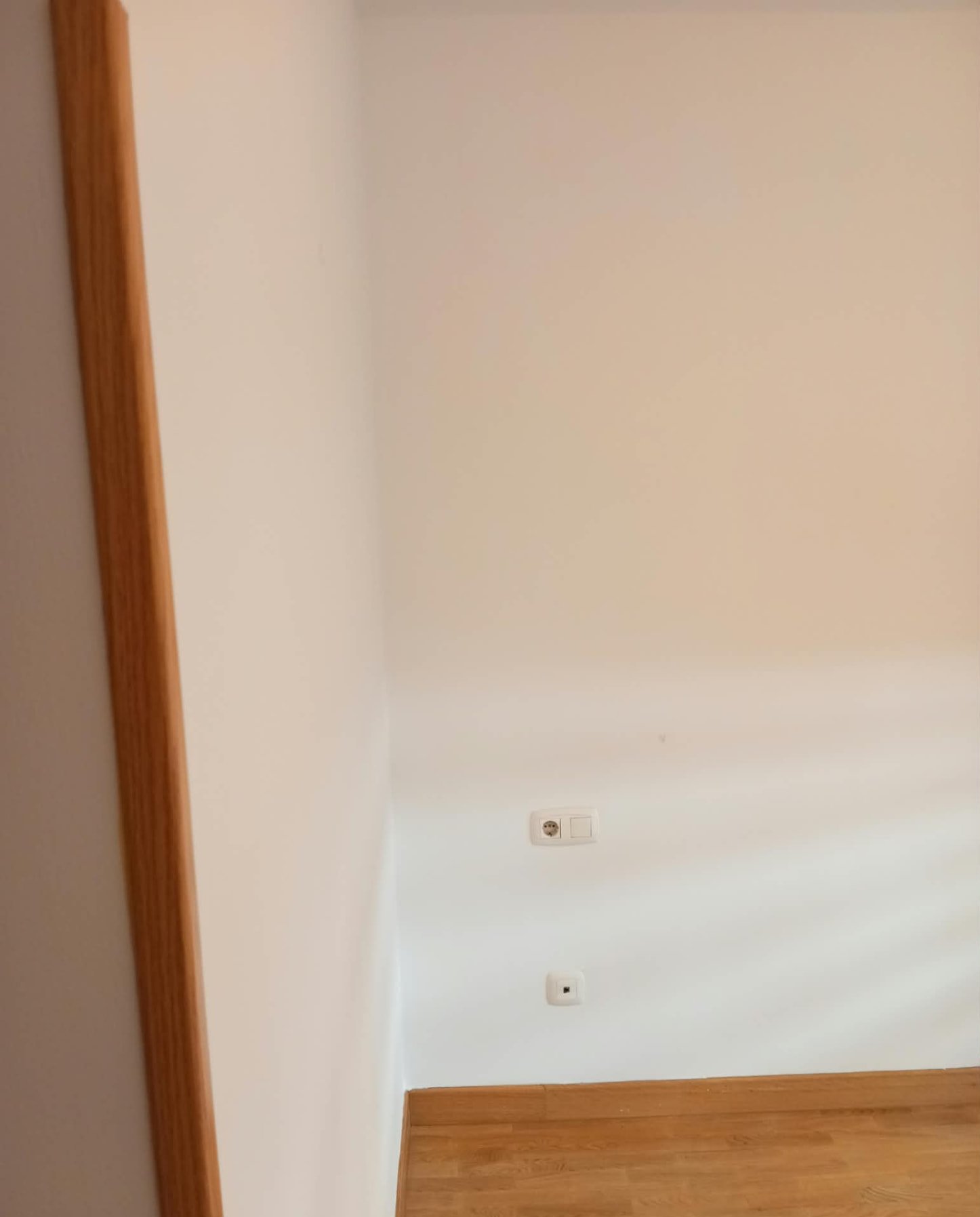 Pared pintada en blanco con rodapié y suelo de madera