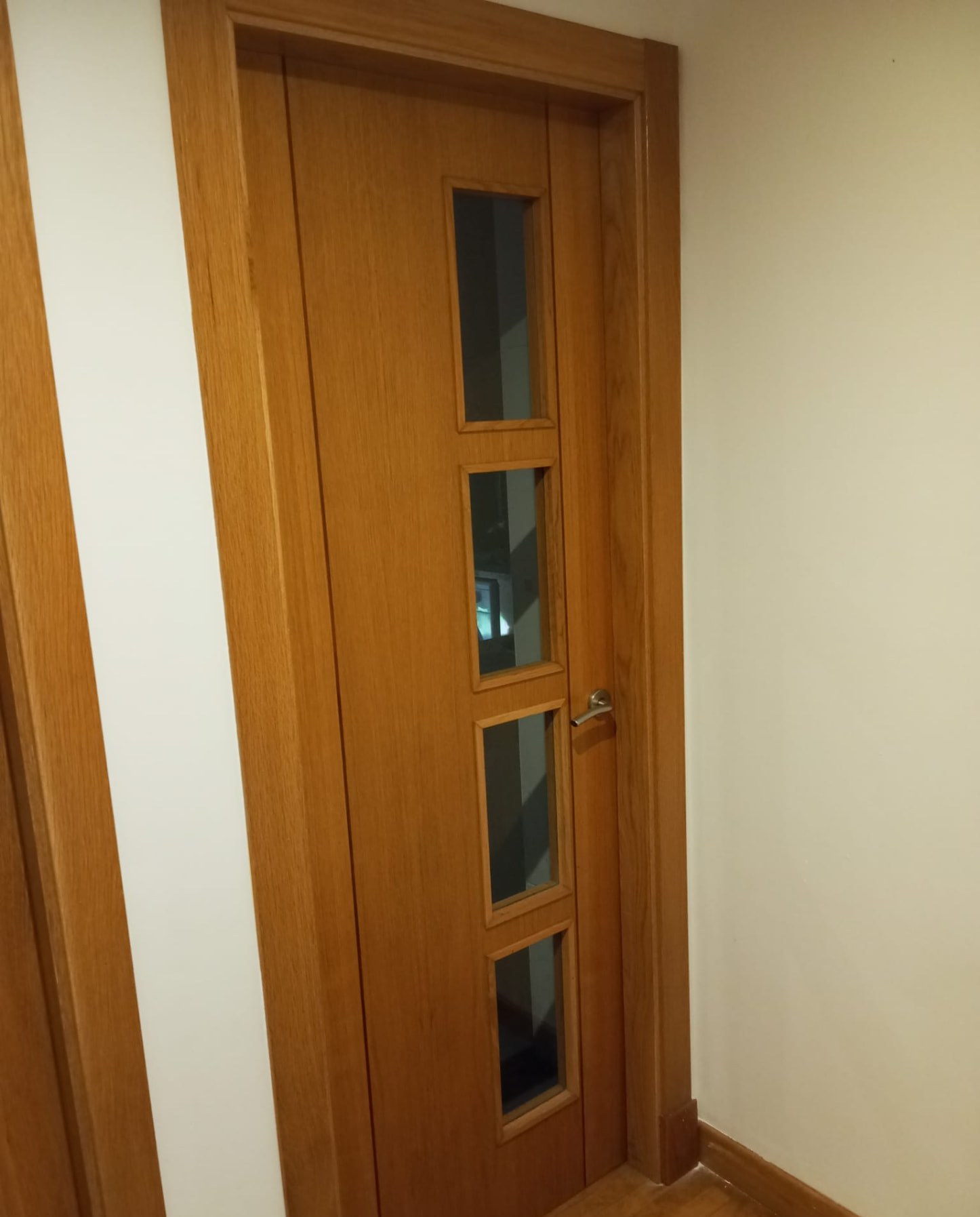 Puerta de madera barnizada con cuatro cristales junto a pared pintada