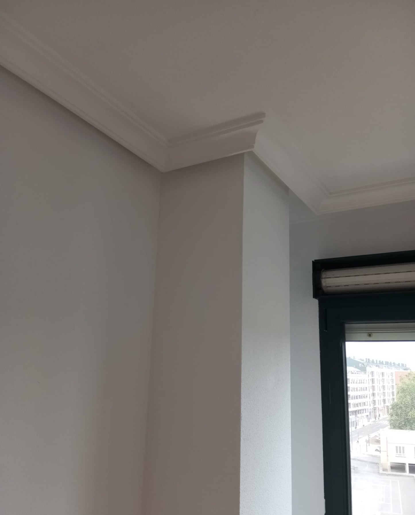 Esquina de techo con molduras y paredes pintadas en blanco