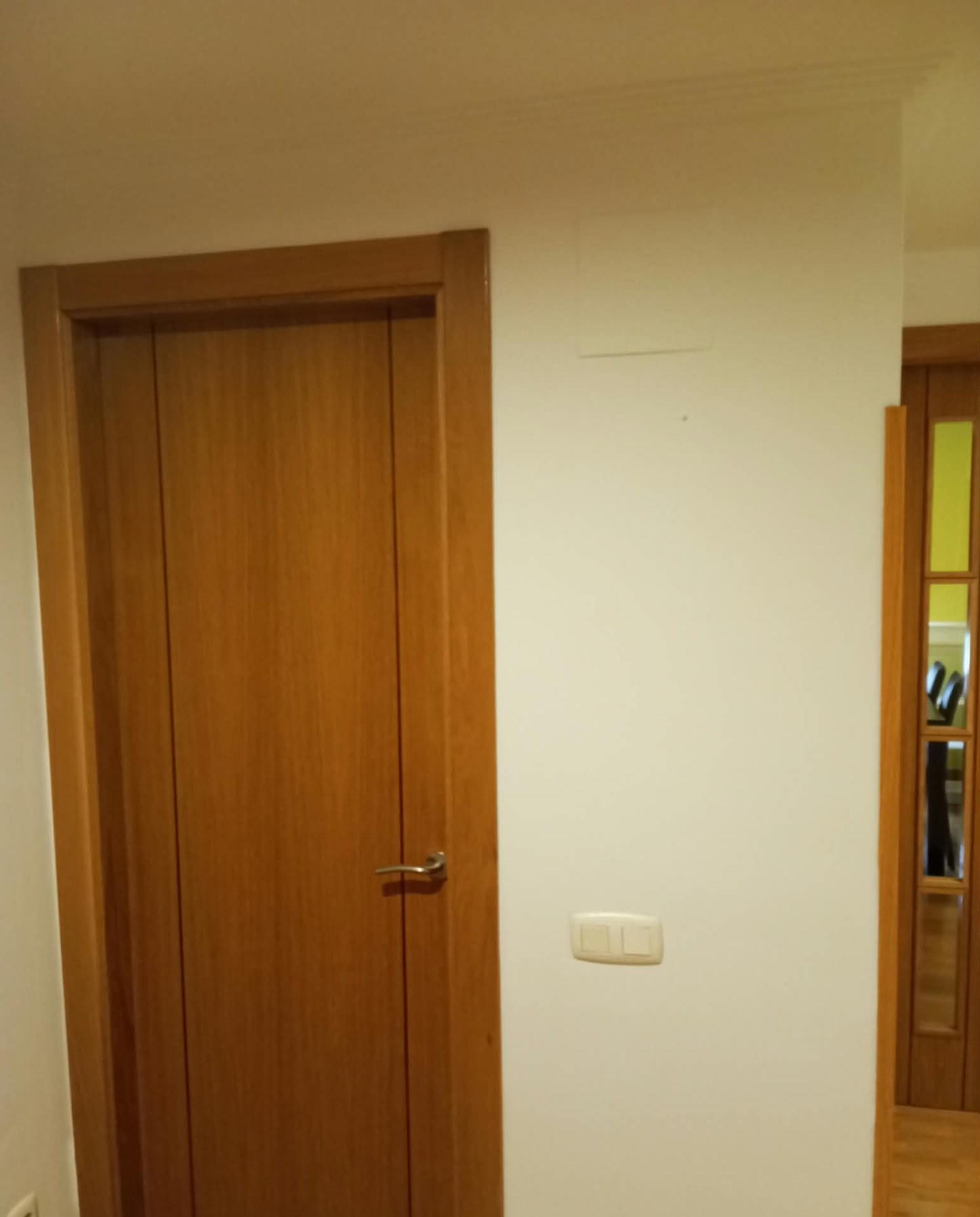 Puerta de madera barnizada junto a pared pintada en blanco