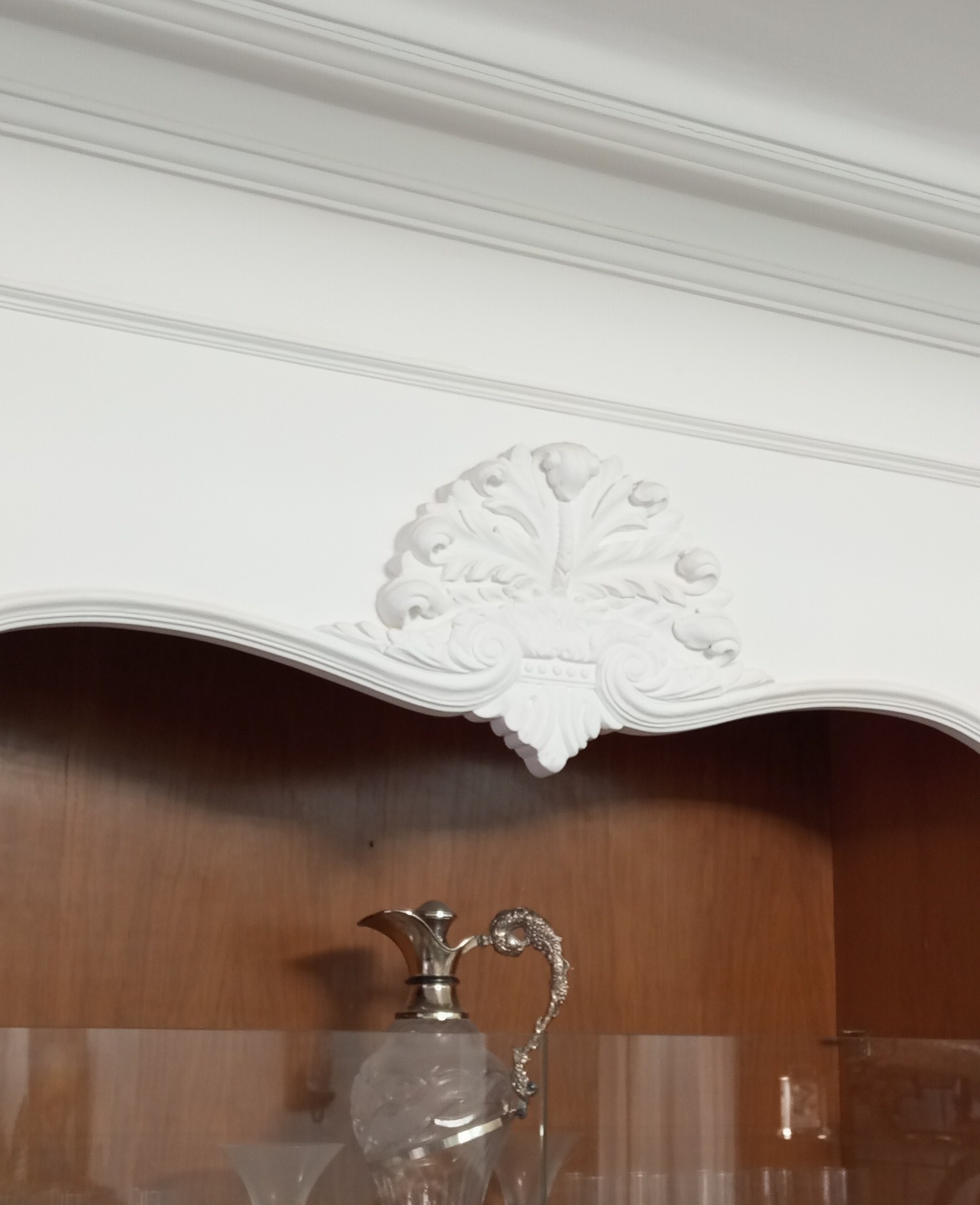 Detalle de adorno ornamentado sobre vitrina lacada en blanco