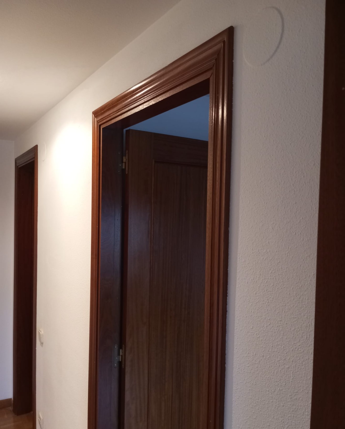 Puerta y marco de madera barnizados con paredes pintadas en blanco