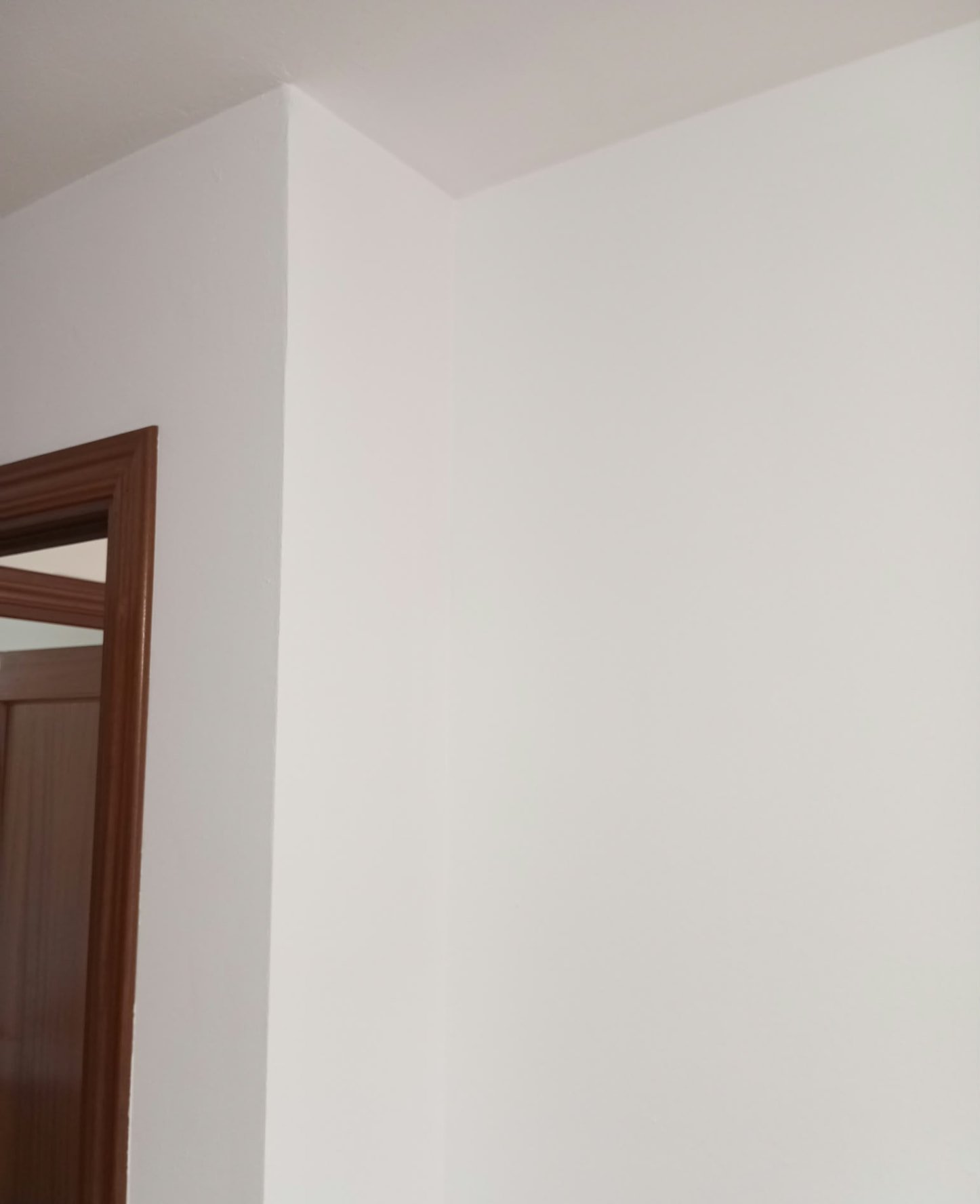 Esquina de pared y techo pintados en blanco con acabado uniforme