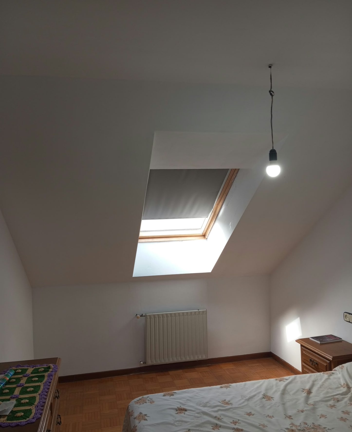 Vista del dormitorio abuhardillado recién pintado con ventana de tejado