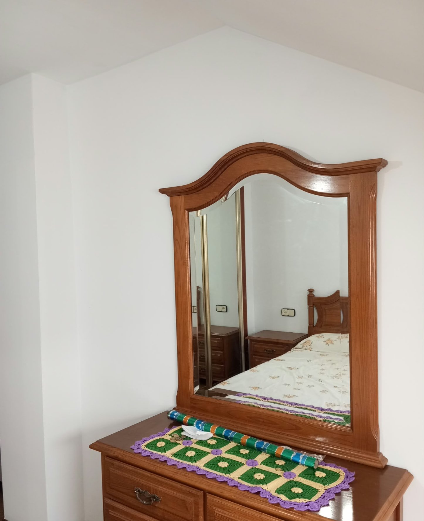 Dormitorio con paredes blancas y cómoda con espejo de madera