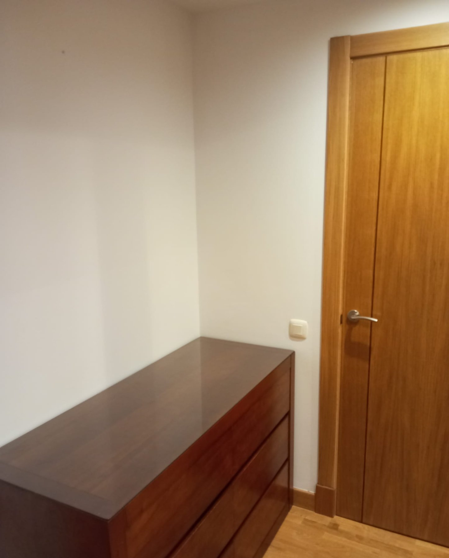 Dormitorio con paredes blancas y cómoda de madera