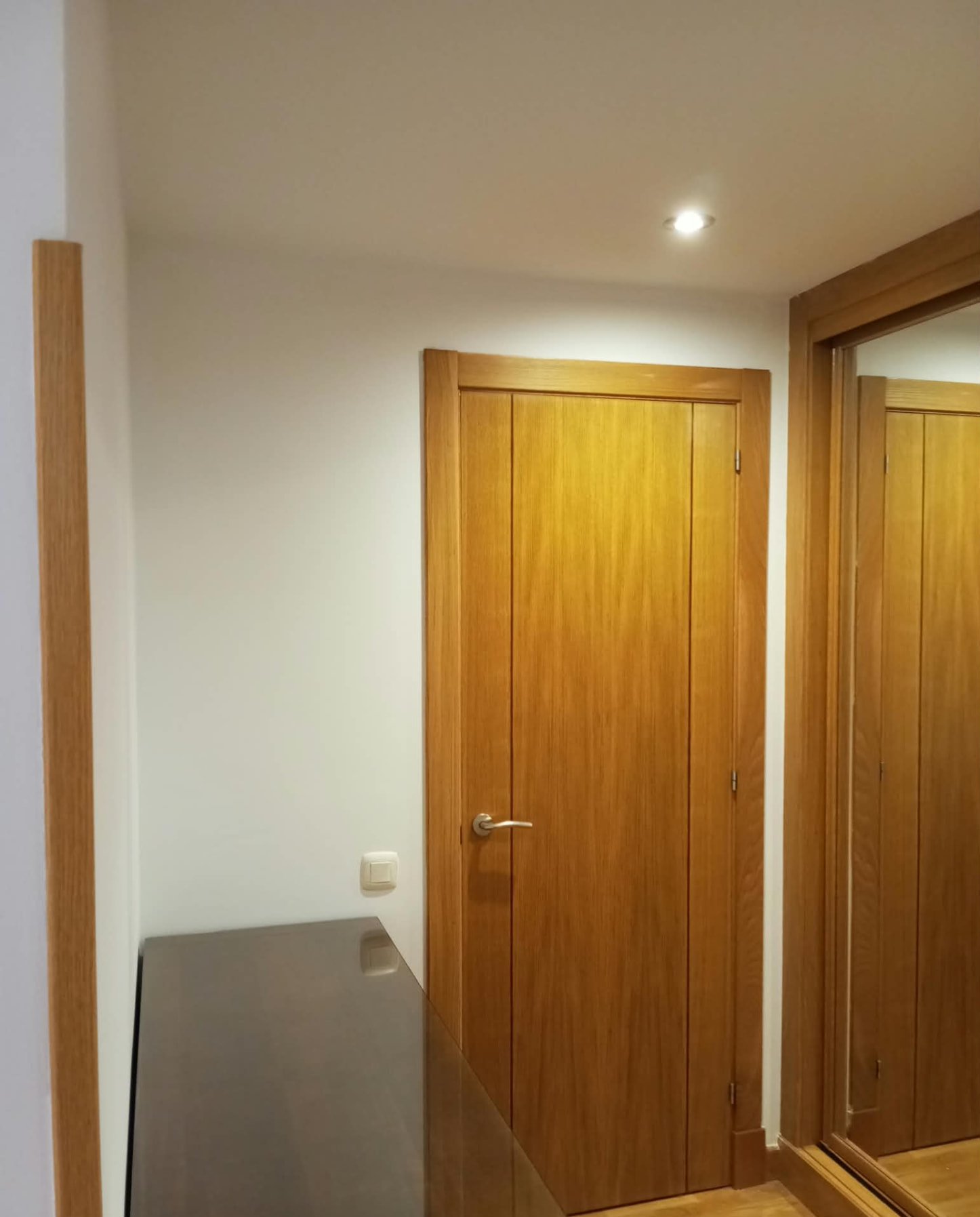 Dormitorio pintado en blanco con puerta de madera barnizada