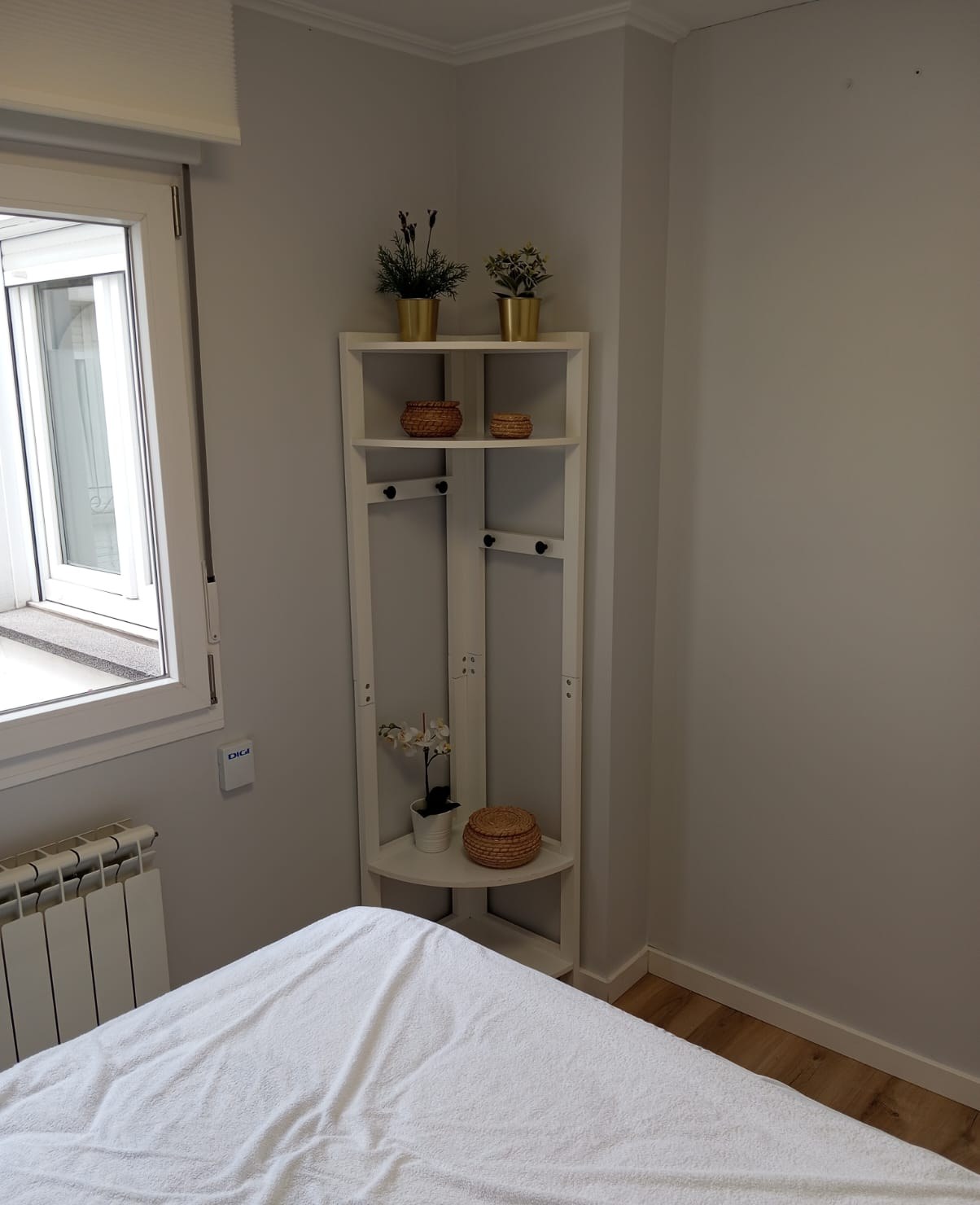 Dormitorio pintado en gris claro con estantería esquinera