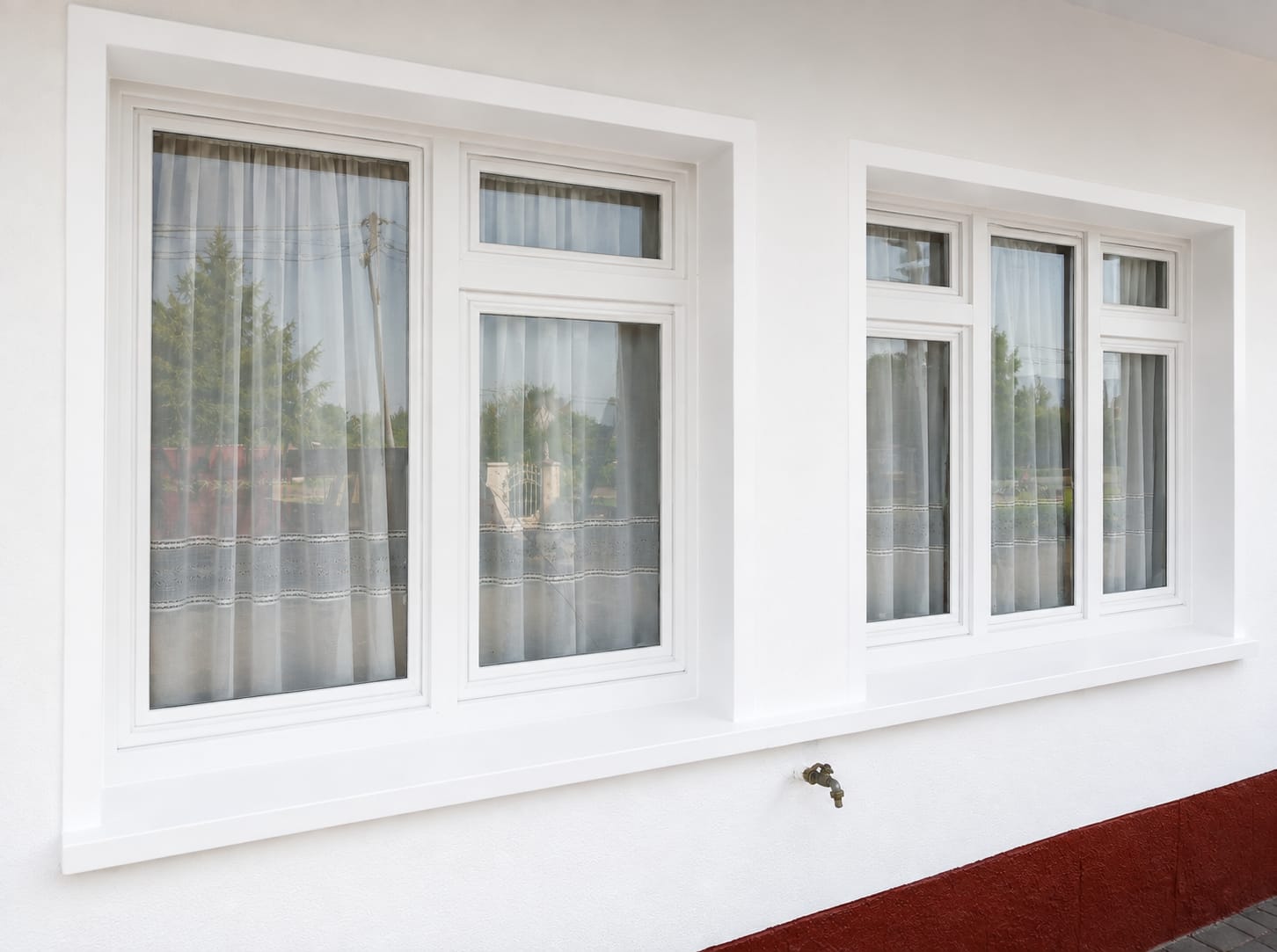 Fachada pintada en blanco con ventanas de carpintería blanca