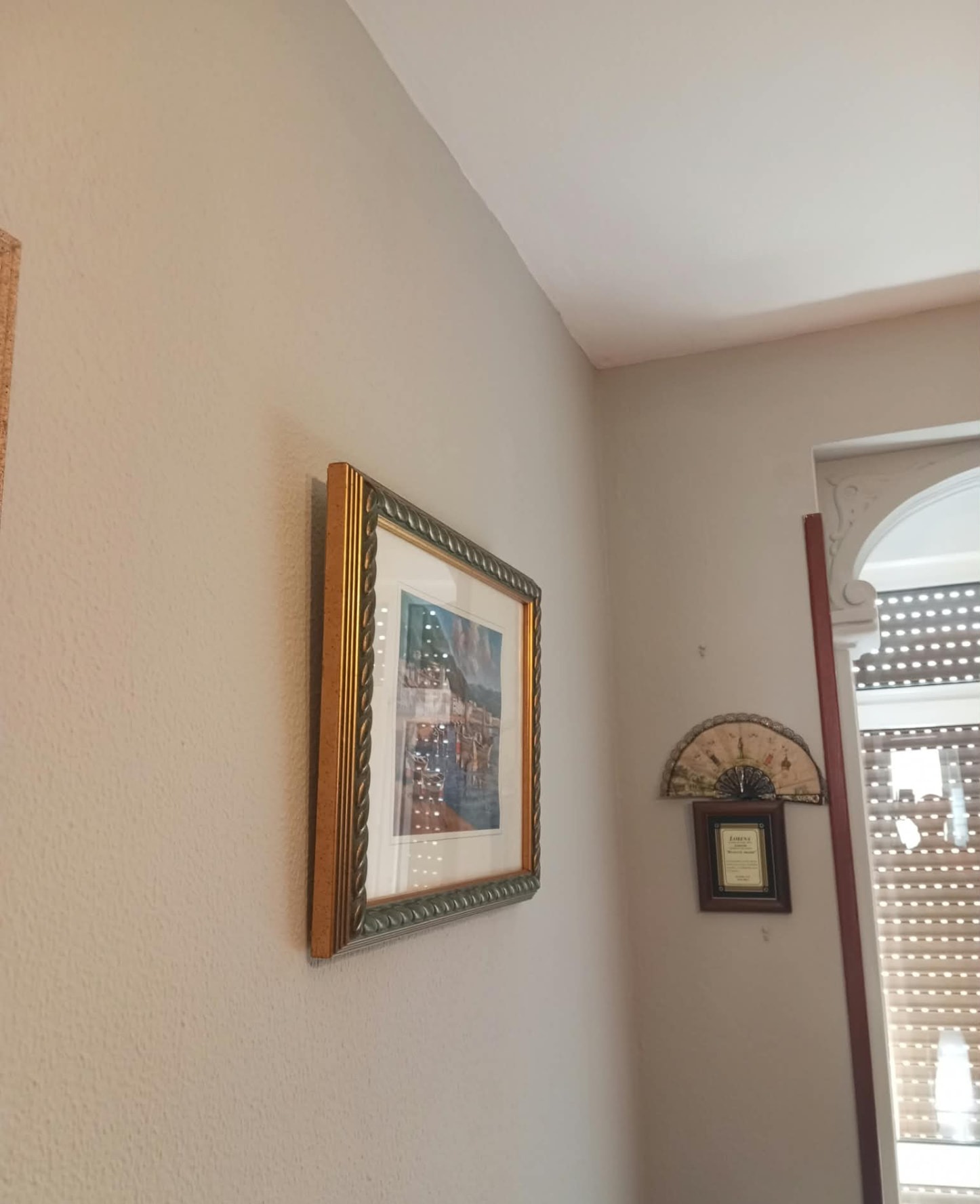 Pared de salón pintada en tono claro junto a ventanal con moldura