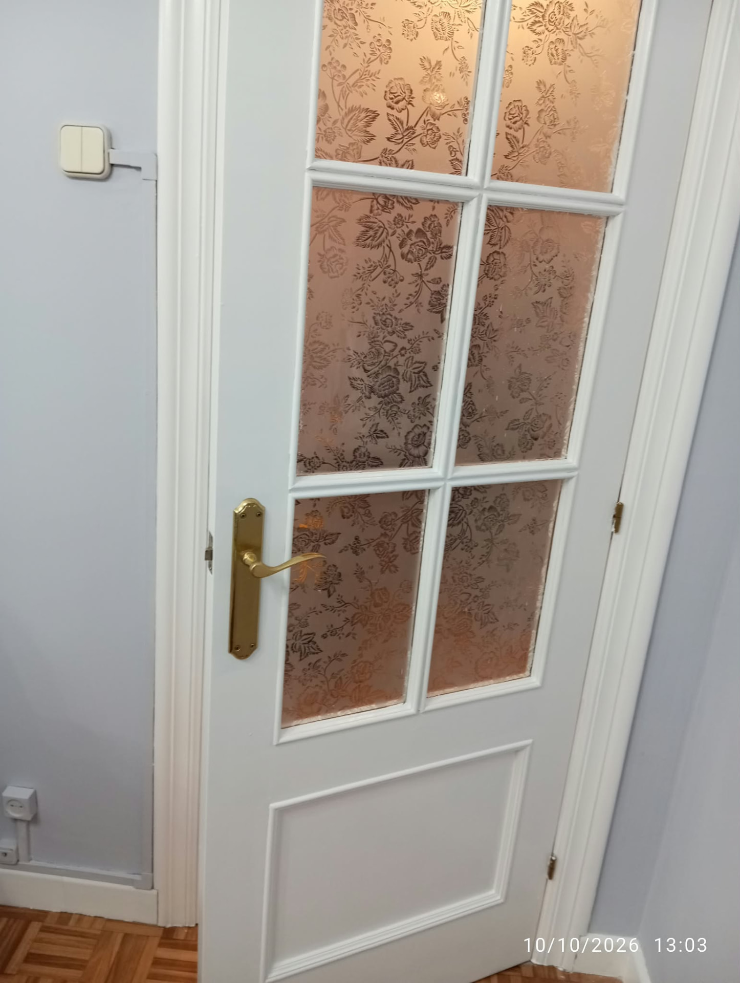 Detalle de puerta lacada en blanco con cristal floral y manilla dorada