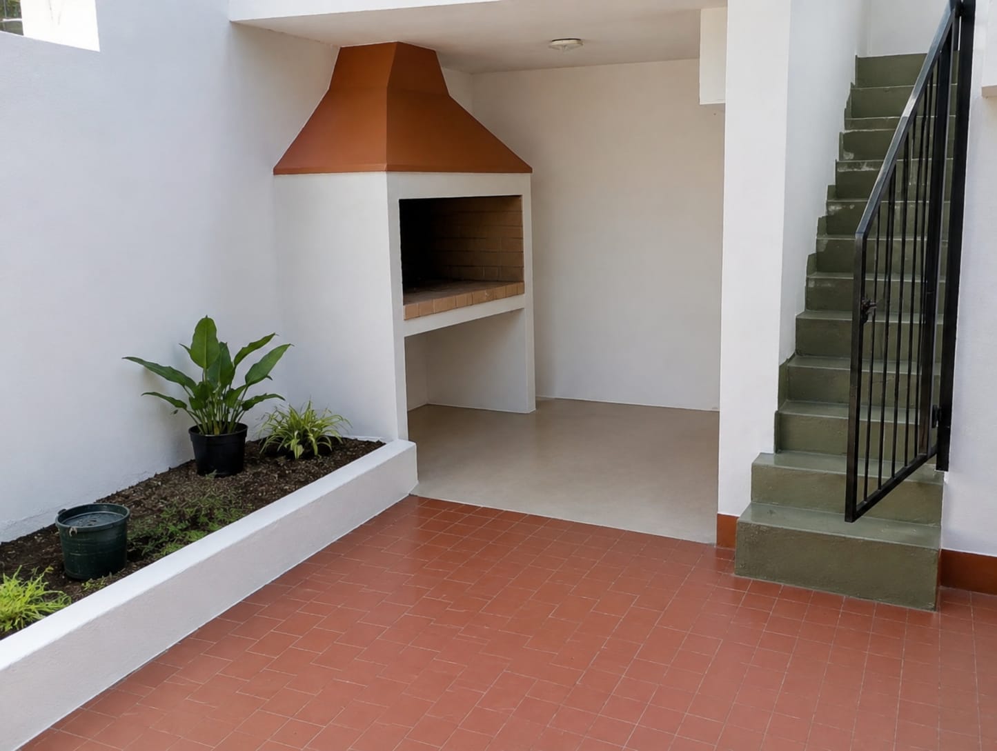 Patio con barbacoa de obra, paredes pintadas y escalera con barandilla