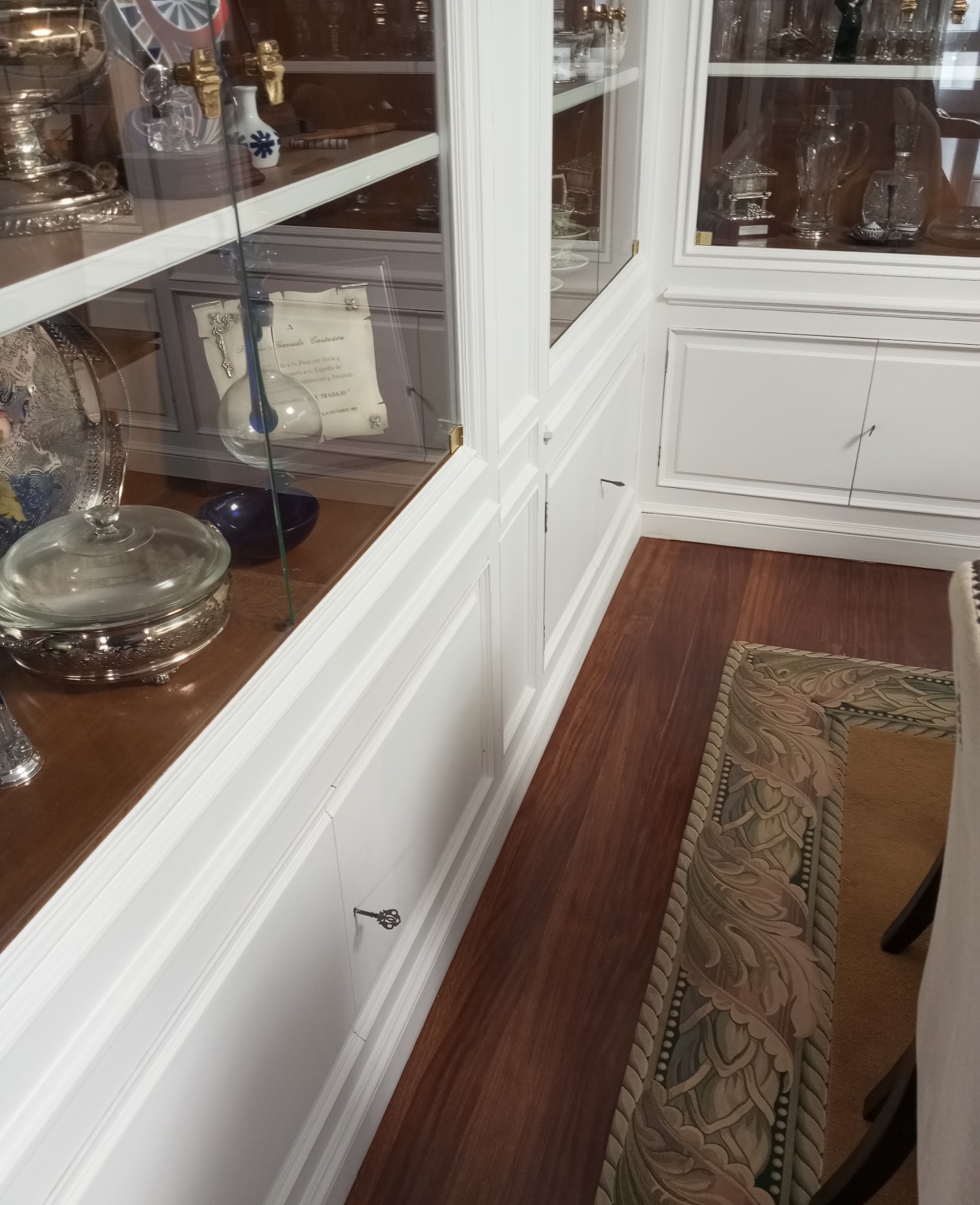 Base de vitrina lacada en blanco con molduras junto a suelo de madera