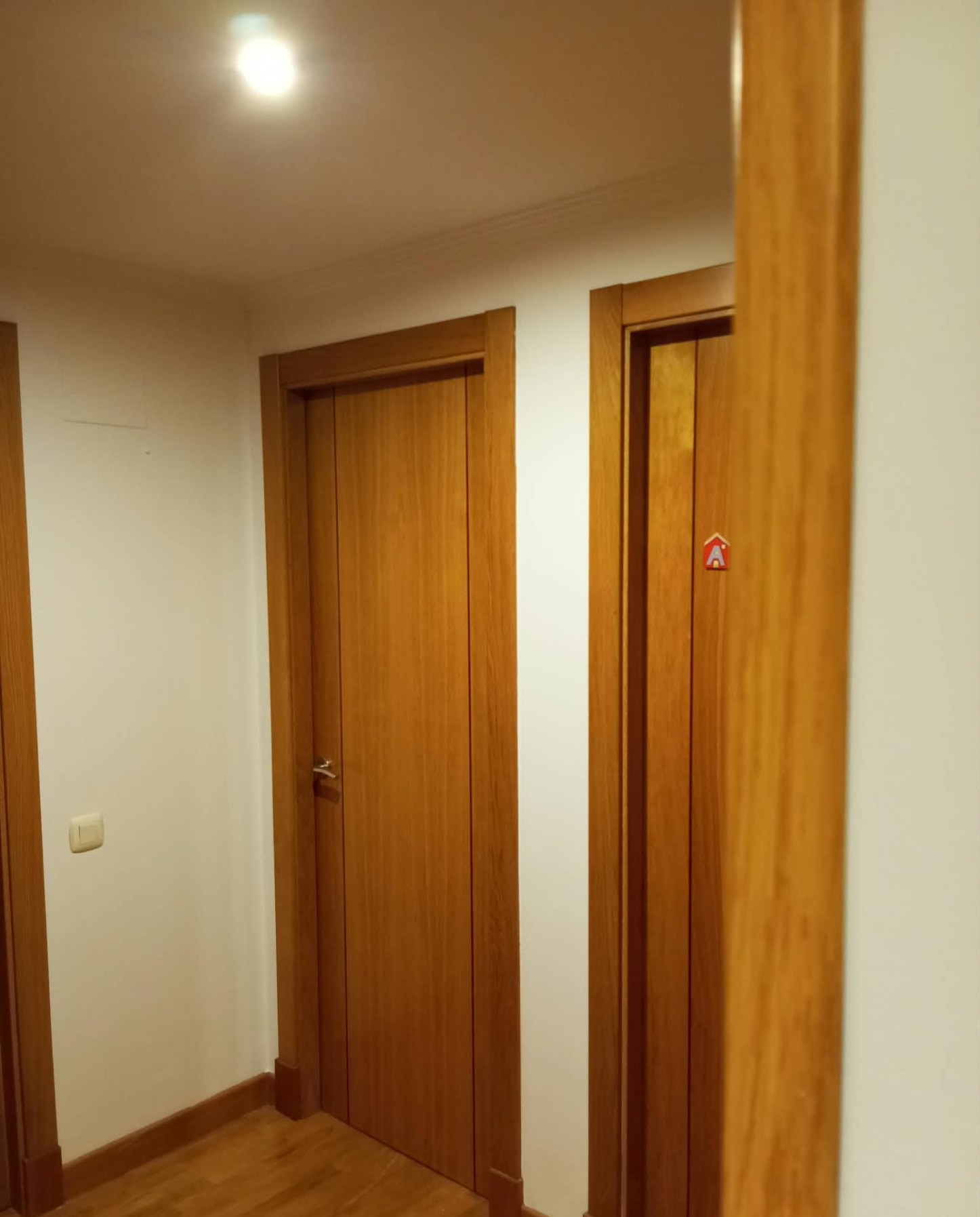 Distribuidor pintado en blanco con puertas de madera y suelo de parquet