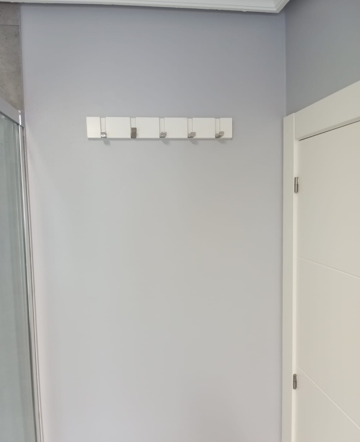 Baño con pared gris lila pintada y percheros