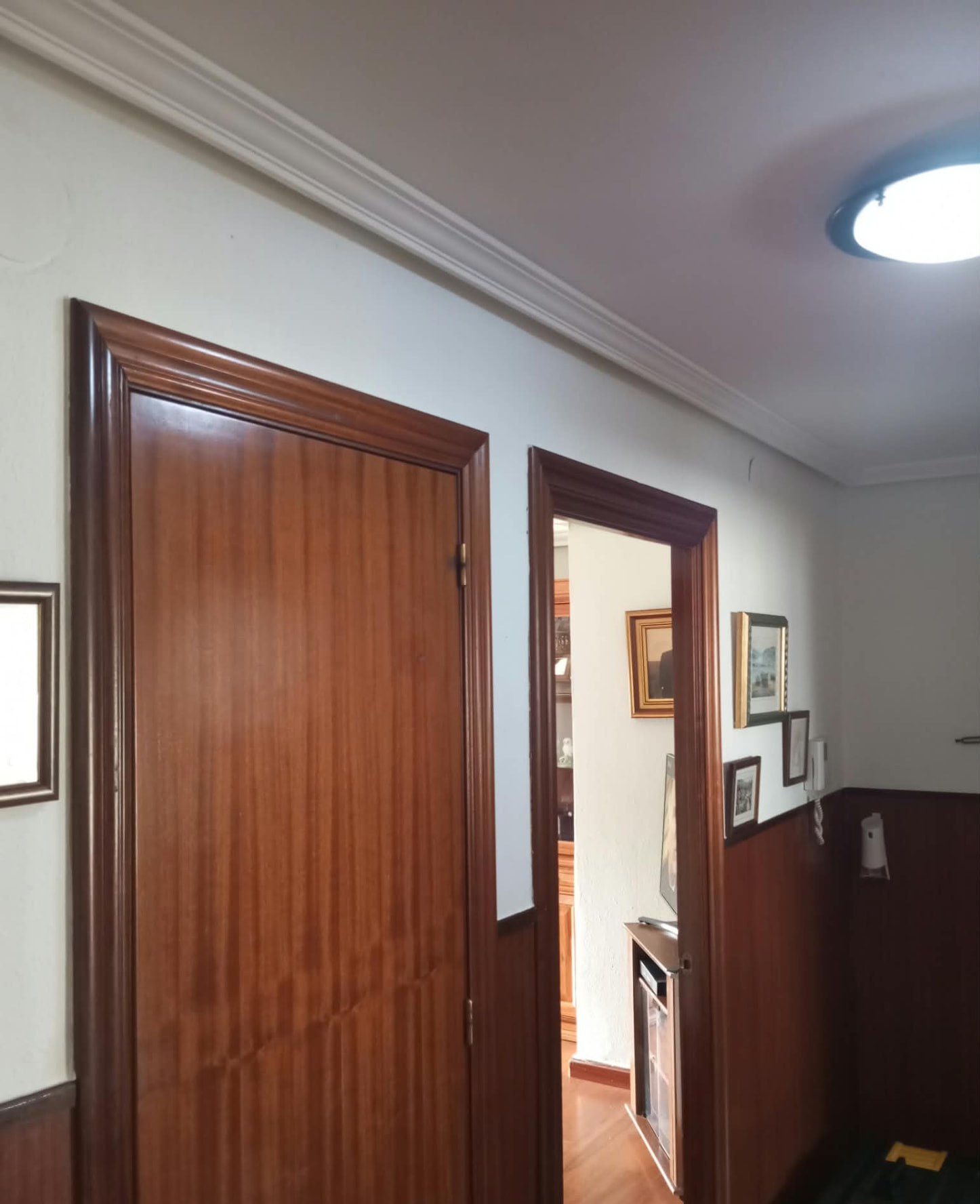 Pasillo con paredes blancas, molduras de techo y puertas barnizadas
