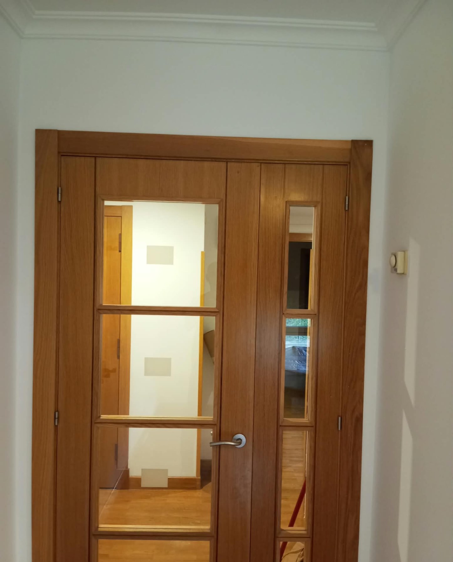 Puerta doble de madera barnizada con cristales y paredes blancas