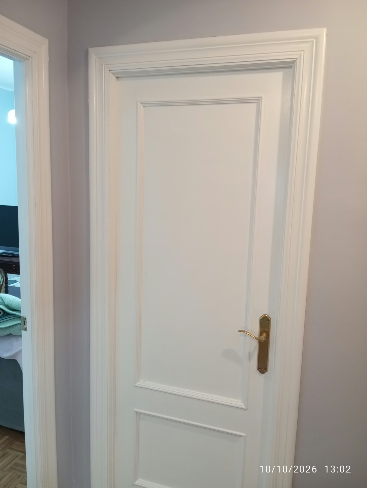 Puerta lacada en blanco entreabierta con marco de molduras