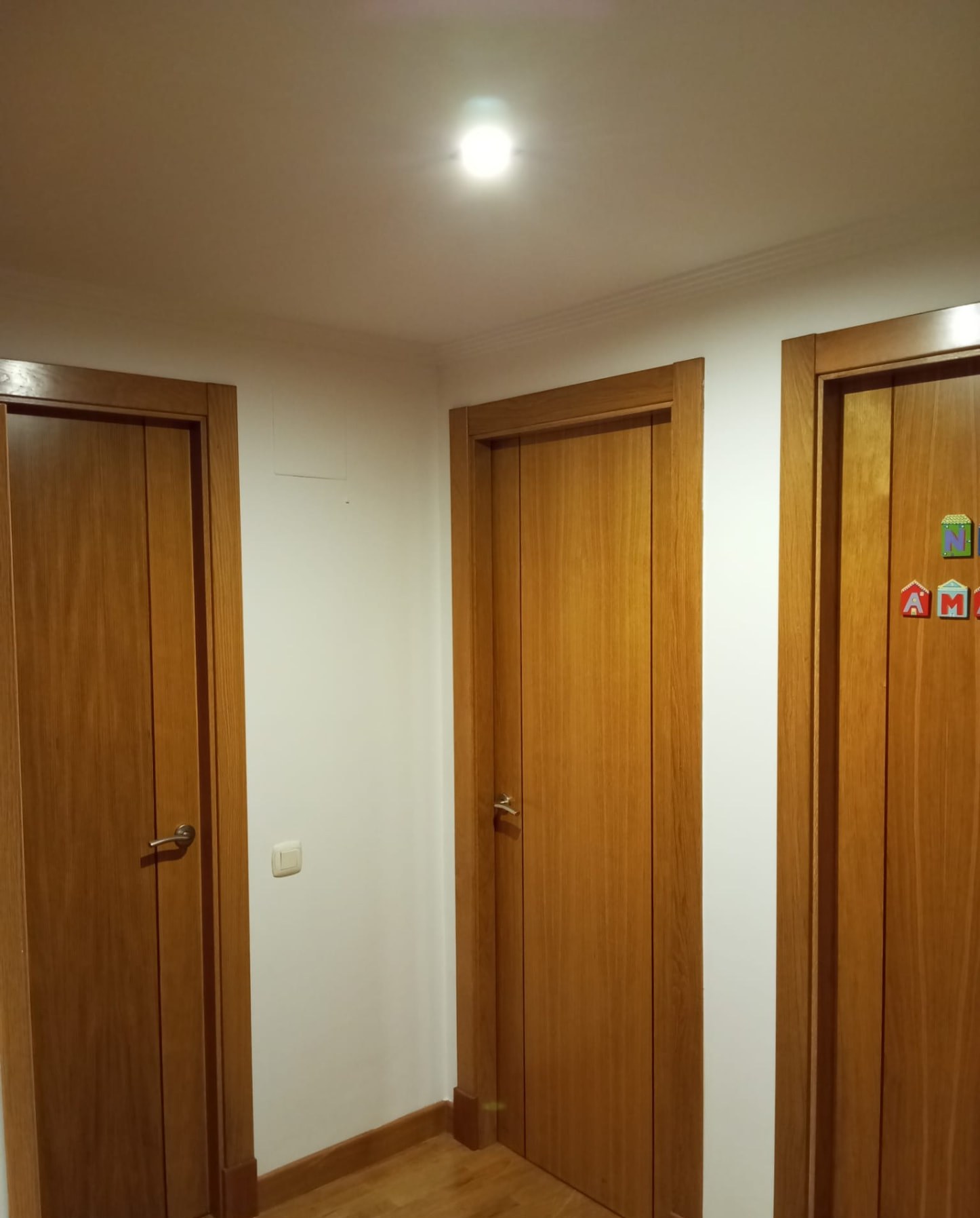 Distribuidor con tres puertas de madera barnizada y paredes blancas
