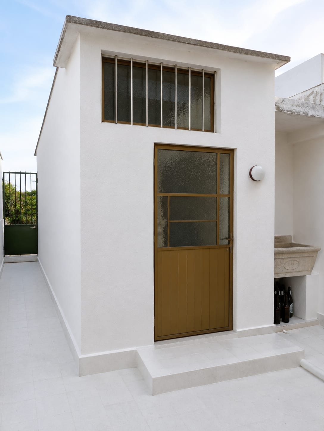 Fachada de anexo pintada en blanco con puerta y ventana barnizadas