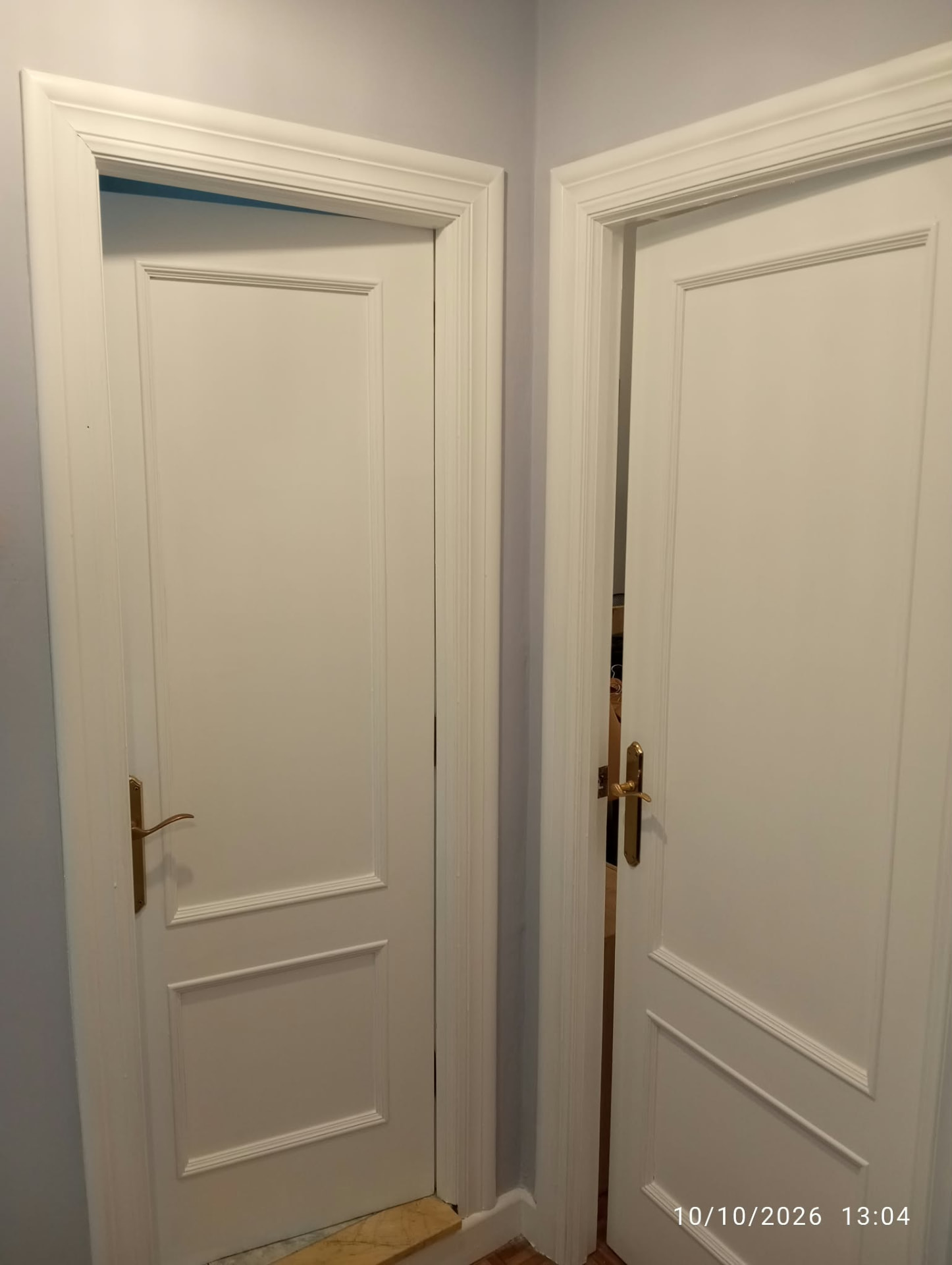 Dos puertas lacadas en blanco con marcos de molduras en pasillo