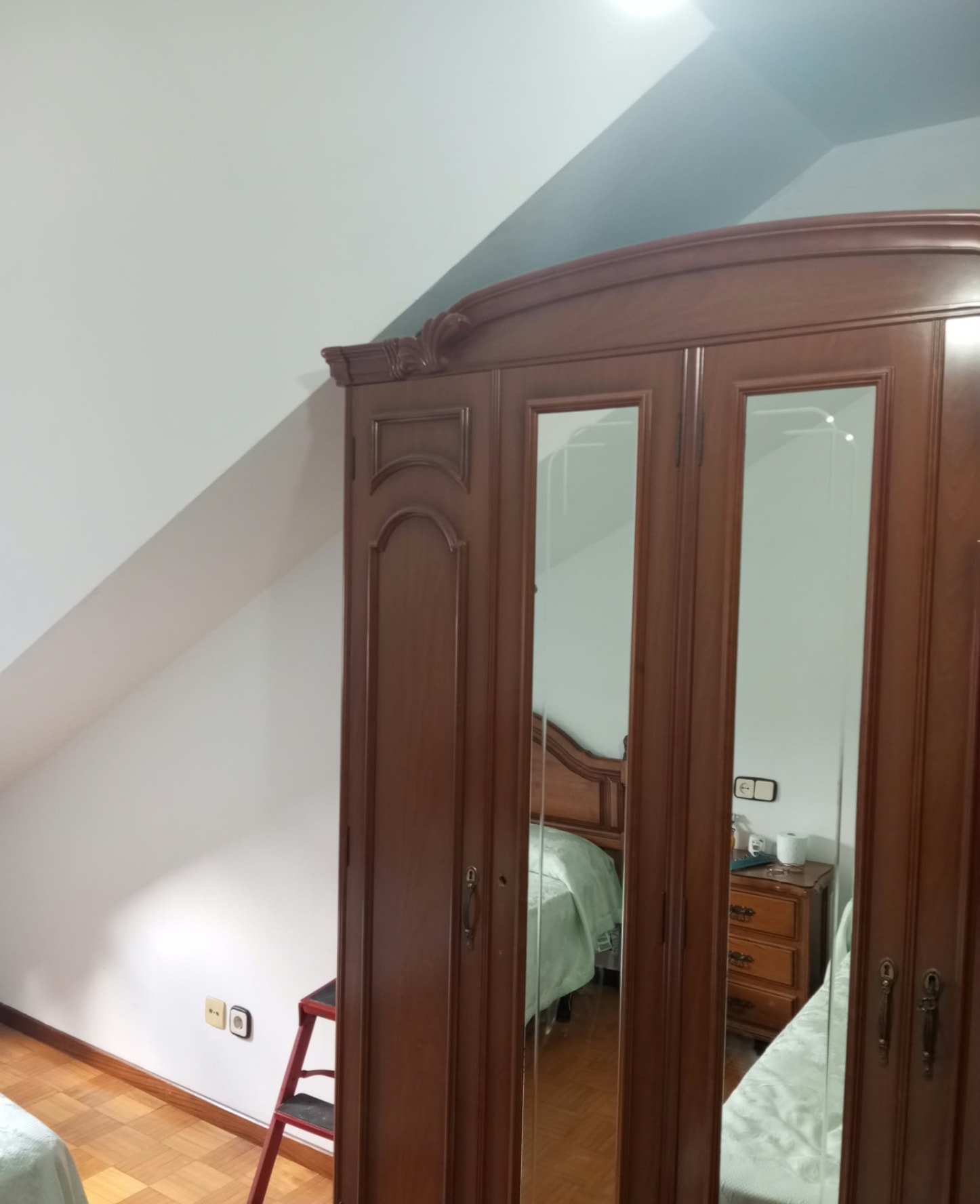 Dormitorio abuhardillado pintado en blanco con armario de madera